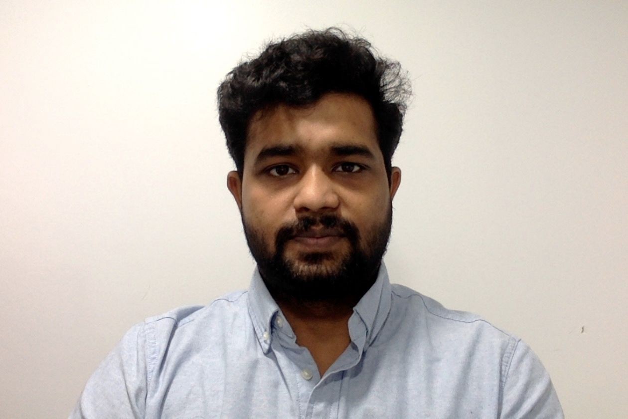 Person wearing a light blue button-up shirt against a plain white background.